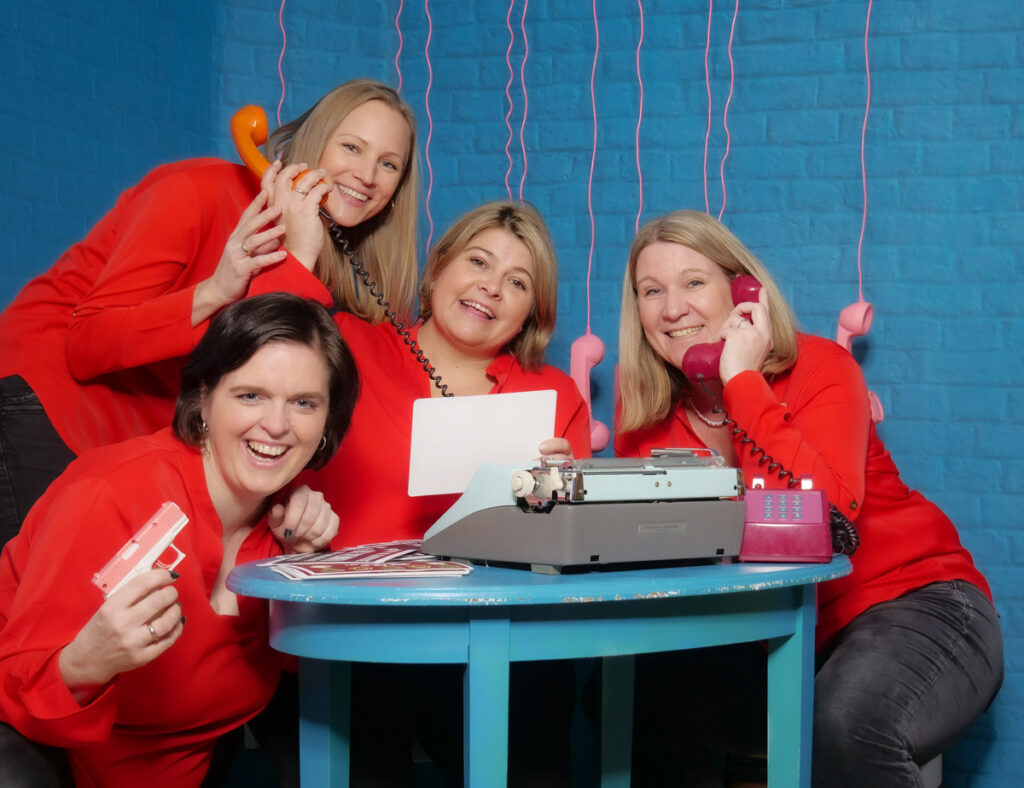 Lustiges Team vor einer blauen Ziegelwand und Telefonen bei einem SELFIE TEAM EVENT im Selfiestudio