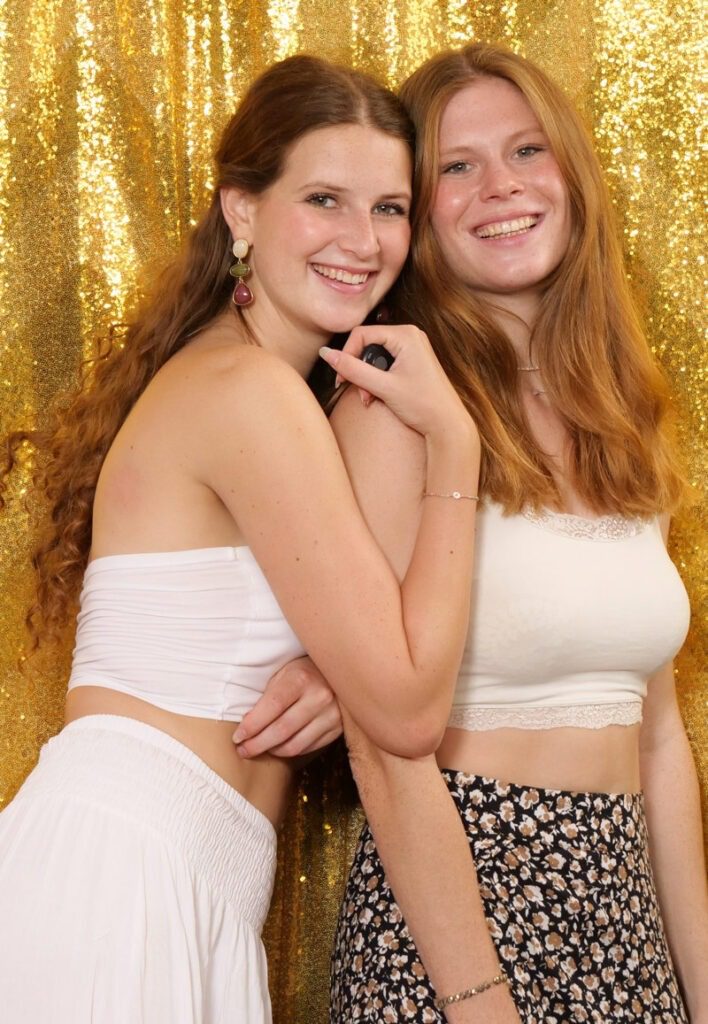 Zwei fröhliche Mädchen beim Selfie Shooting vor einem goldenen Hintergrund